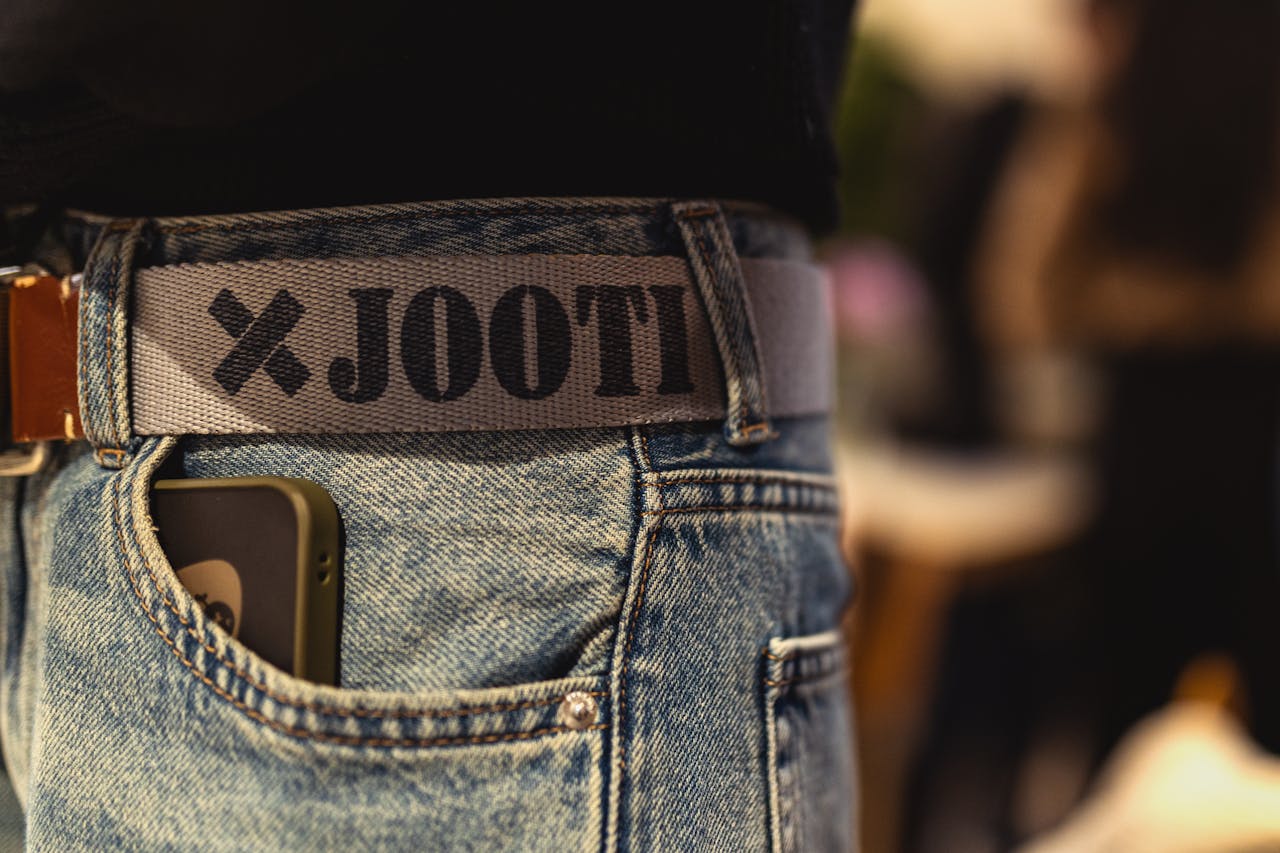 home-hero-2 Stylish jeans with a branded belt and smartphone, captured at a Berlin fashion event.